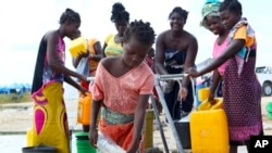 Várias mulheres e meninas buscam água num campo de deslocados para sobreviventes do ciclone Idai, Beira, Moçambique, 2 de Abril, 2019.