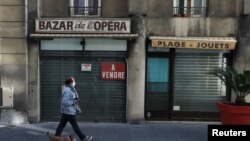 FILE - A woman walks his dog past a closed shop during the second national lockdown as part of the measures to fight a second wave of the coronavirus disease in Nice, France, Nov. 17, 2020. 