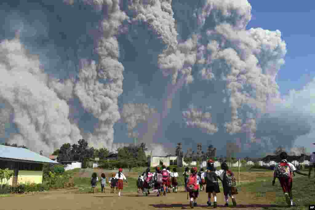 School children walk as Mount Sinabung erupts in Karo, North Sumatra, Indonesia, Feb. 19, 2018.
