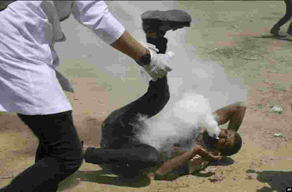 A Palestinian medic rushes to a a protester who got shot in his mouth by teargas canister fired by Israeli troops near the Gaza Strip's border with Israel, east of Khan Younis, June 8, 2018. Thousands of Palestinians are streaming toward the fence separating Gaza from Israel for a protest against the decade-long blockade of their territory.