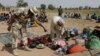 FILE- Soldiers guard people fleeing from Boko Haram’s carnage, Dec. 8, 2015. People detained by the military and a civilian self-defense force are disappearing in northeast Nigeria some wrongly accused of fighting for Boko Haram.