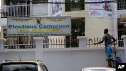 FILE - A man paints the fence of electoral commission ELECAM's offices in Yaounde, Cameroon, Oct. 10, 2018. 