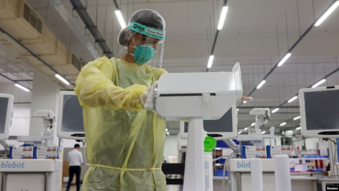 An operator wearing personal protective equipment wipes down the coronavirus disease swab test robot called SwabBot during a demonstration in Singapore Sept. 25, 2020. 