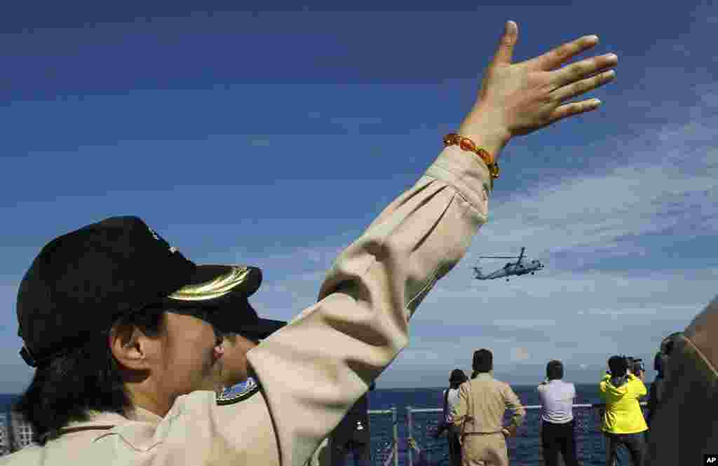 2013年5月16日,一名軍官向從台灣一艘基德級驅逐艦的艦艉起飛的直升機揮手。