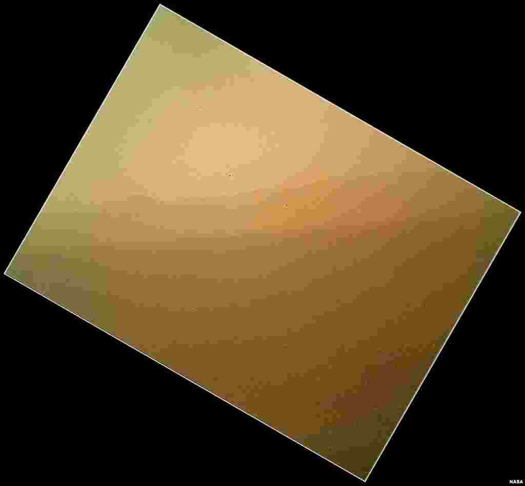 This image shows the first color view of the north wall and rim of Gale Crater where Curiosity landed. The picture was taken by the rover's camera at the end of its stowed robotic arm and appears fuzzy because of dust on the camera's cover.