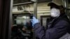 FILE - A New York subway rider wears protective gloves and a mask while holding onto a pole, March 19, 2020.