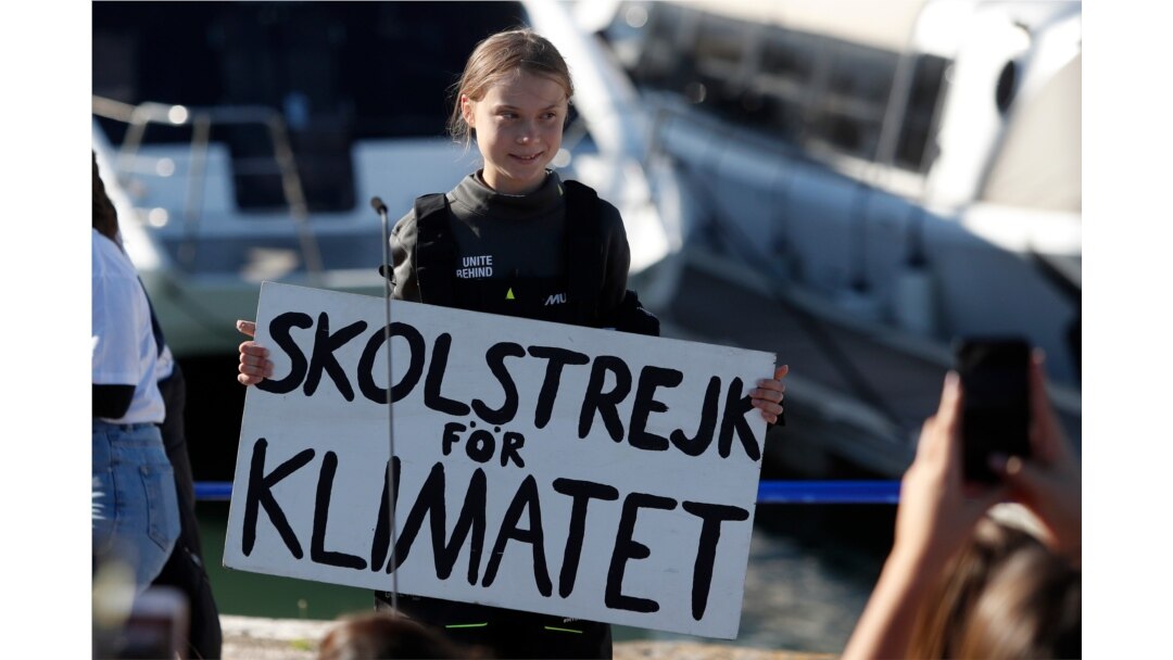 Climate activist Greta Thunberg holds a sign reading 'School strike for the climate' after arriving in Lisbon, aboard the sailboat La Vagabonde, Dec 3, 2019.