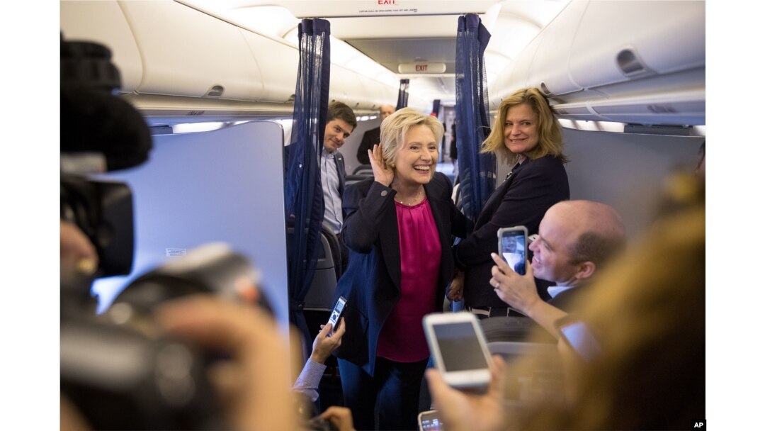 FILE - Democratic presidential candidate Hillary Clinton, accompanied by traveling press secretary Nick Merrill, left, and director of communications Jennifer Palmieri, right, listens to a question from a member of the media on her campaign plane.