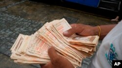 Un hombre cuenta billetes por el equivalente a un dólar en una parada de autobús en Caracas, el 5 de agosto de 2021.