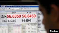 A currency trader works in front of a screen showing the value of the Indian rupee against the U.S. dollar on the floor of a trading firm in Mumbai, May 31, 2013. 