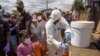 FILE - In this photo taken April 24, 2020, residents are given bottles of a herbal mixture said to prevent and cure COVID-19 in Antananarivo, Madagascar. 