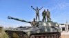 FILE - In this photo released by the Syrian official news agency SANA, Syrian army soldiers flash the victory sign as they stand on their tank in the village of Kfar Nabuda, in the countryside of Hama province, Syria, May 11, 2019.