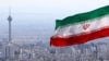 FILE - Iran's national flag flutters in the wind as the Milad telecommunications tower and buildings are seen in the background, Tehran, Iran, March 31, 2020. 