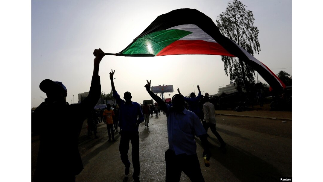 Sudanese demonstrators wave their national flag as they arrive for a protest rally demanding Sudanese President Omar Al-Bashir to step down outside the Defense Ministry in Khartoum, Sudan, April 11, 2019.