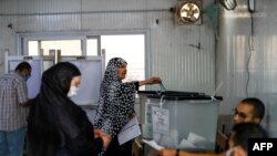 A woman arrives to vote as another casts her ballot in parliamentary elections, at a polling station in the Talibeya district of Giza, Egypt, Oct. 24, 2020.