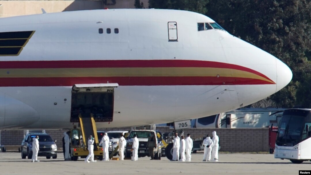 Personal con ropa protectora se acerca al avión contratado por el Departamento de Estado de EE.UU. para evacuar empleados gubernamentales de China tras el brote de coronavirus, tras arrivar a la Base Aérea March en Riverside, California, el miércoles, 29 de enero de 2020.