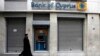 A Greek Orthodox priest walks a branch of Bank of Cyprus in Athens March 19, 2013.