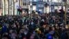 FILE - Crowds of shoppers walk under the Christmas lights in Regent Street, in London, Saturday, Dec. 12, 2020. 