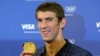 FILE - Michael Phelps poses with his gold medal for the 4x100m medley relay during a news conference with his sponsors at the London 2012 Olympic Games, August 5, 2012. 