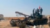 In this Aug. 13, 2019 photo, released by the Syrian official news agency SANA, Syrian army soldiers flash the victory sign as they stand on a tank, in northwestern Syria. 
