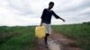 Woman carries water collected from a broken main water supply pipe in Kambuzuma, Harare (2009 photo)