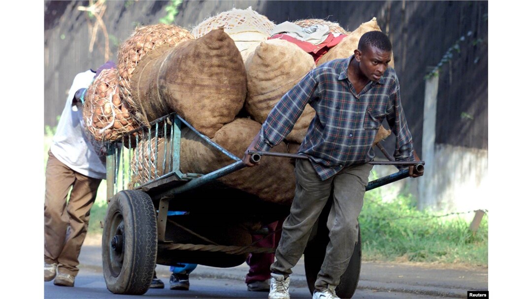 FILE - Young men carting sacks of potatoes to the market encounter a steep hill just outside Nairobi, Kenya, June 13, 2001.
