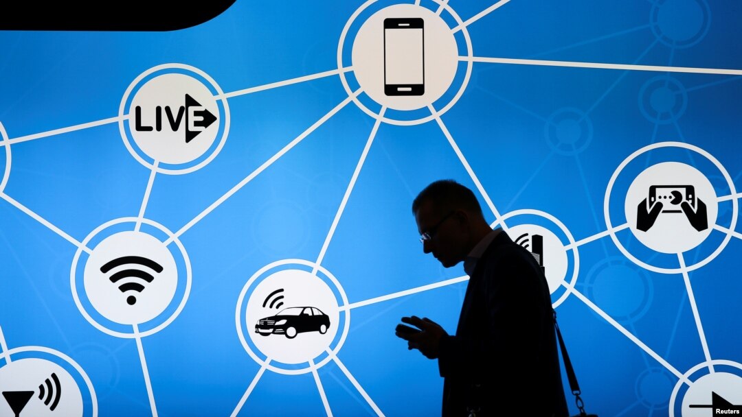 A man looks at his phone in front of a stand at the Mobile World Congress in Barcelona, Spain, showing a variety of devices connected via Wi-Fi and Internet of Things networks, Feb. 28, 2017