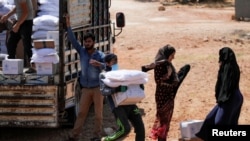 FILE - A worker holds bags and a box of humanitarian aid in the opposition-held Idlib, Syria June 9, 2021.