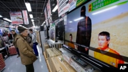 日本東京一名市民在商店內觀看電視新聞報導日本人質事件