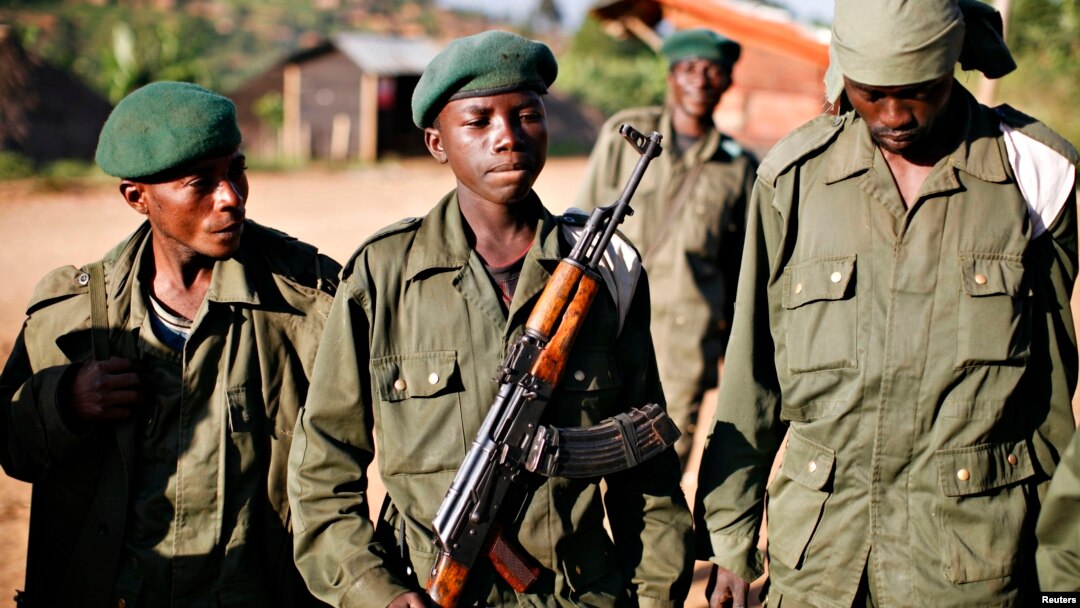 A child soldier (C), known as "Kadogo," meaning "small one" in Swahili, stands at the front line at Kanyabayonga in eastern Congo, November 17, 2008. 