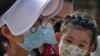 FILE - A woman and a child wearing face masks to protect against the new coronavirus visit a shopping mall in Beijing, Aug. 2, 2020.