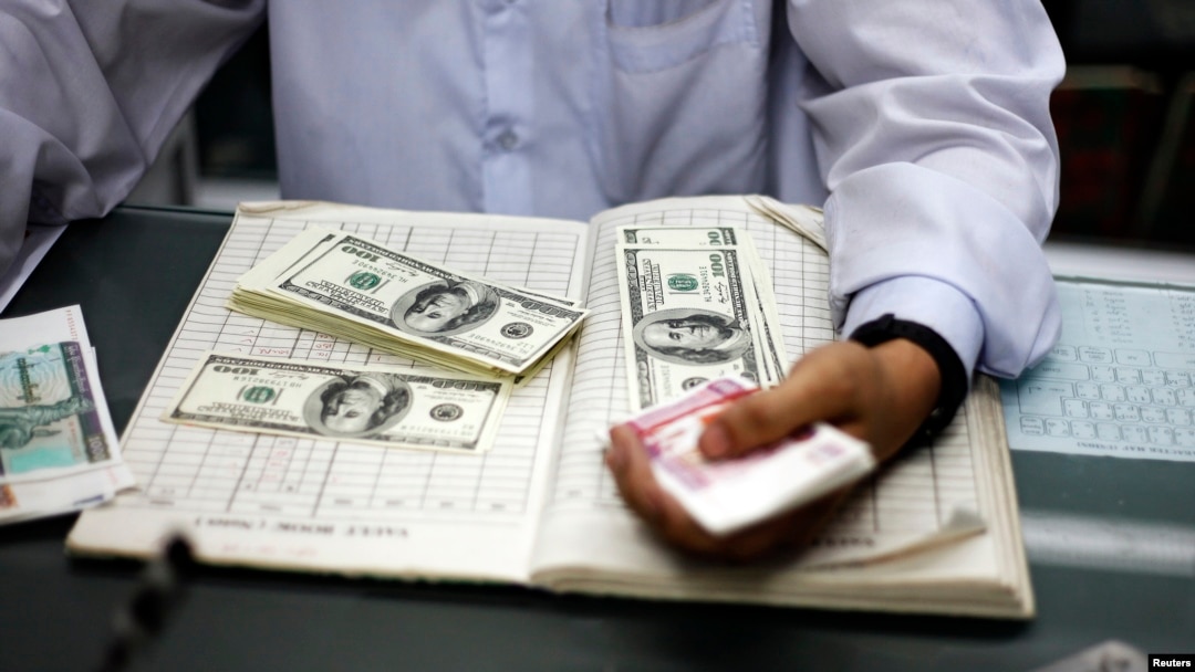 Myanmar man counts US dollars and Myanmar kyats