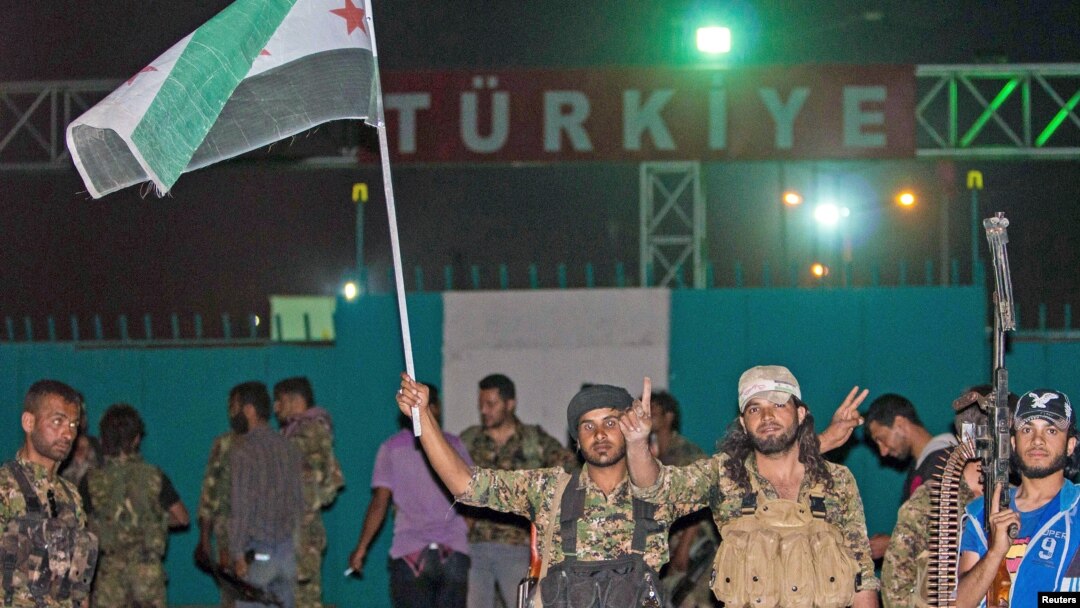 FILE - Fighters from the Kurdish People's Protection Units and Free Syrian Army's Al-Tahrir Brigade gesture while posing on the Syrian-Turkish border Tel Abyad of Raqqa governorate after they said they took control of the area, June 15, 2015.