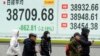 People walk in front of an electronic stock board showing Japan's Nikkei index at a securities firm, Feb. 3, 2025, in Tokyo.