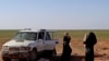 FILE - Two women, wives of an Islamic State fighter who has been identified as a German national, wait to be screened and registered by Syrian Democratic Forces, in the countryside of the eastern Syrian Deir Ezzor province, Jan. 31, 2019.