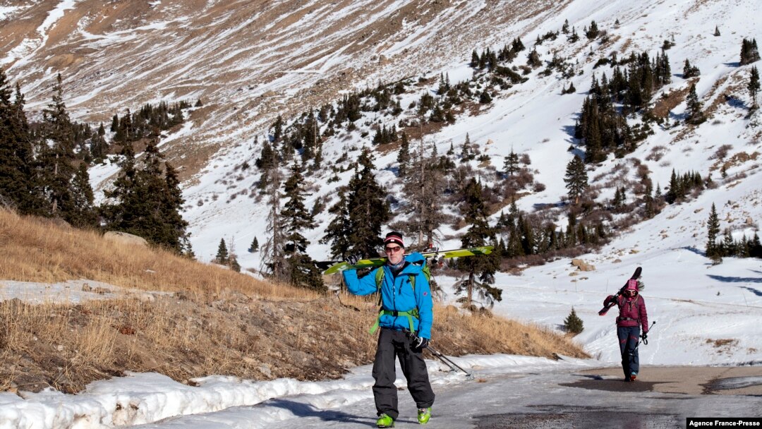 Glenn Cain (L) of Alma, Colorado and Mary Taylor of Silverthorne, Colorado walk on exposed pavement after backcountry skiing in Summit County, Colorado on Dec. 3, 2021. 