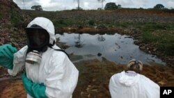 Waste removal experts work to extract hazardous black sludge from a garbage dump in Abidjan, Ivory Coast, September 17, 2006. (AP)