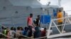 FILE - A police officer speaks to rescued migrants after they arrived on an Armed Forces of Malta patrol boat in Valletta's Marsamxett Harbour, Malta, Sept. 21, 2019. 