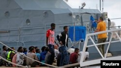 FILE - A police officer speaks to rescued migrants after they arrived on an Armed Forces of Malta patrol boat in Valletta's Marsamxett Harbour, Malta, Sept. 21, 2019. 