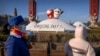 People wearing face masks to protect against coronavirus look at a display of the Winter Paralympic mascot Shuey Rhon Rhon, left, and Winter Olympic mascot Bing Dwen Dwen near the Olympic Green in Beijing, Jan. 12, 2022. 
