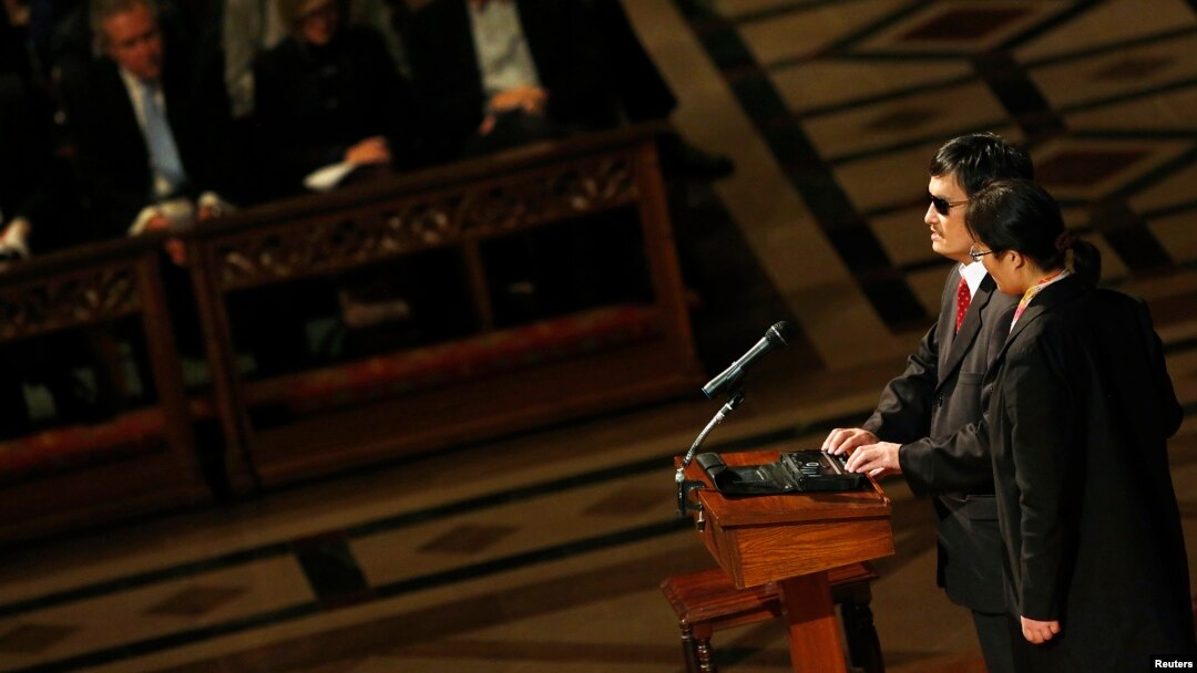 Blind Chinese activist Chen Guangcheng (2nd R), standing with his wife Yuan Weijing, delivers remarks at the National Cathedral in Washington, January 30, 2013. 