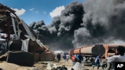 People are seen in front of clouds of black smoke from fires in the aftermath at the scene of an airstrike in Mekele, the capital of the Tigray region of northern Ethiopia, Oct. 20, 2021. 