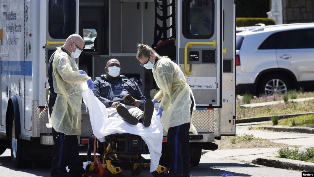 Emergency Medical Technicians lift a patient that was identified to have coronavirus disease into an ambulance while wearing protective gear, in New York City, New York, March 26, 2020.