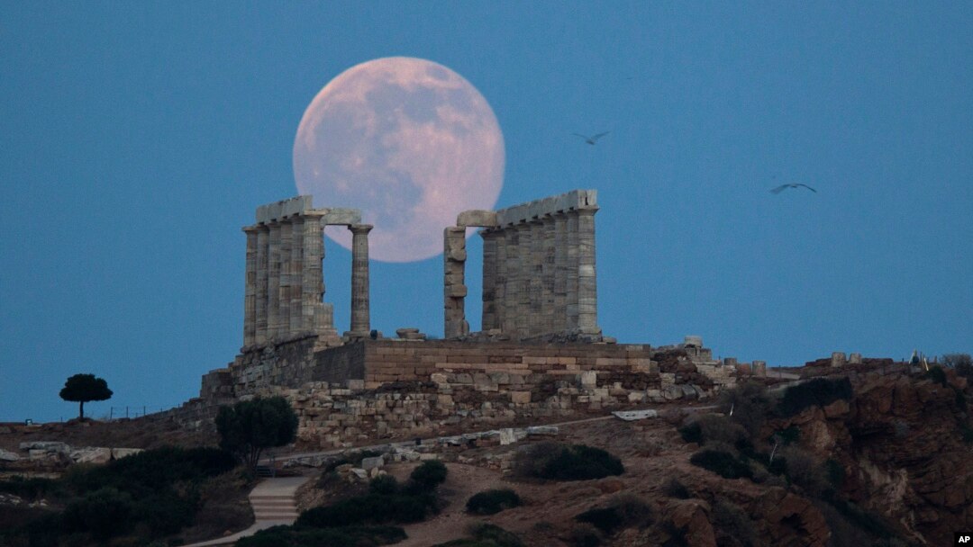 FILE - Seagulls fly as the full moon rises behind the ancient marble Temple of Poseidon at Cape Sounion, southeast of Athens, on the eve of the summer solstice, June 20, 2016.