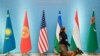 FILE - A security officer with a sniffer dog passes national flags, from left, Kazakh, Kyrgyz, U.S., Uzbek, Tajik and Turkmen, before leaders gather for a group picture during a meeting of the C5+1 in Tashkent, Uzbekistan, Feb. 3, 2020.