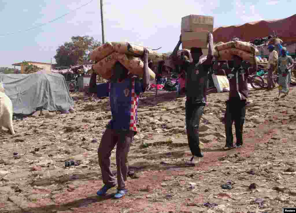 Men carry humanitarian food aid toward boats, Mopti, Mali, February 4, 2013.