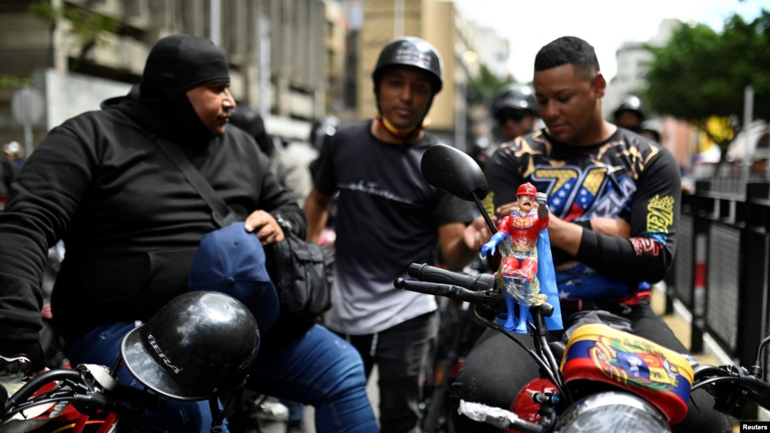 Un muñeco Super Bigote, inspirado en el presidente venezolano, Nicolás Maduro, está unido a una motocicleta de miembros de un grupo de motociclistas, conocido como Fuerza Motorizada, durante un ejercicio militar en Caracas, Venezuela, el 23 de enero de 2025. 