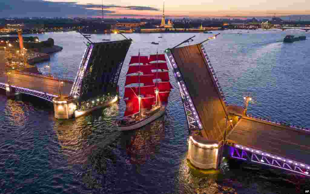 A brig with scarlet sails travels through the Dvortsovy (Palace) drawbridge rising above the Neva River during a rehearsal for the the Scarlet Sails festivities marking school graduation which will take place on June 24 in St. Petersburg, Russia.