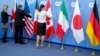 Workers adjust the flags of a Group of Seven meeting in Brussels, Belgium, June 5, 2014. G-7 foreign ministers are meeting Monday and Tuesday in Tuscany, Italy.