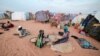 FILE - Fatouma Abubakr, 70, a Sudanese woman who fled the conflict in Sudan's Darfur region, sits with her daughter as she removes waste from millet grain she received from the World Food Program outside their makeshift shelter in Adre, Chad, on Aug. 5, 2023.